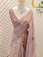 Linen saree with a border is adorned with detailed floral embroidery, possibly using French knots, and features sequins and a decorative woven edge