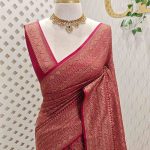 Soft katan with body features floral pattern enclosed within geometric diamond shapes. and a decorative zari border with repetitive linear and floral elements