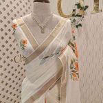 Kerala saree with large lily-like flowers with delicate green stems and leaves.